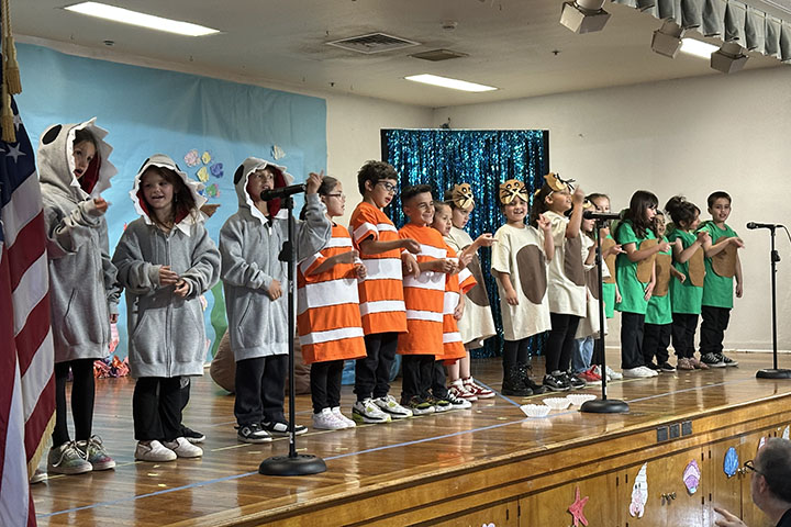 A group of students in costume act out a scene on stage