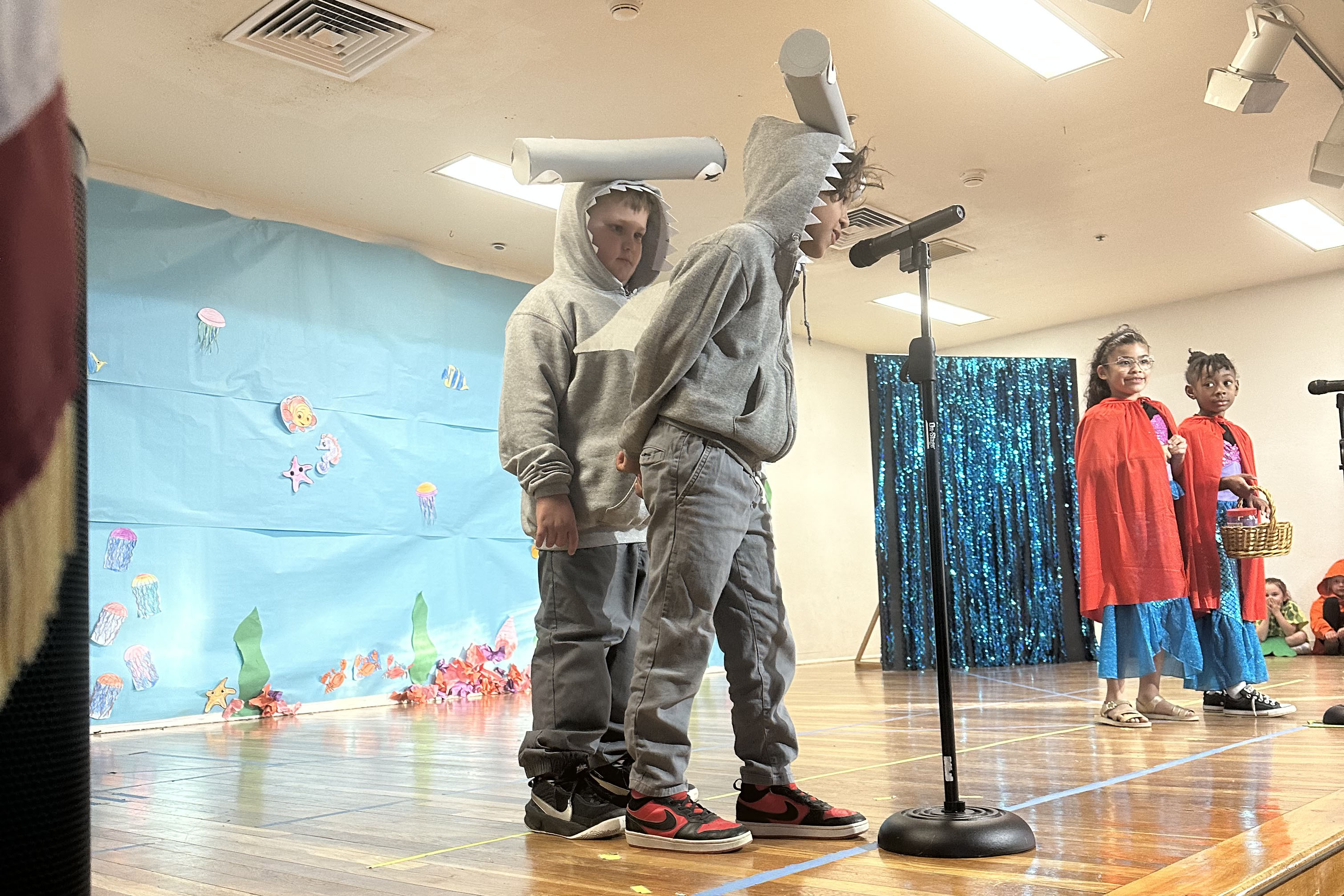 Two students dressed as hammerhead sharks act on stage