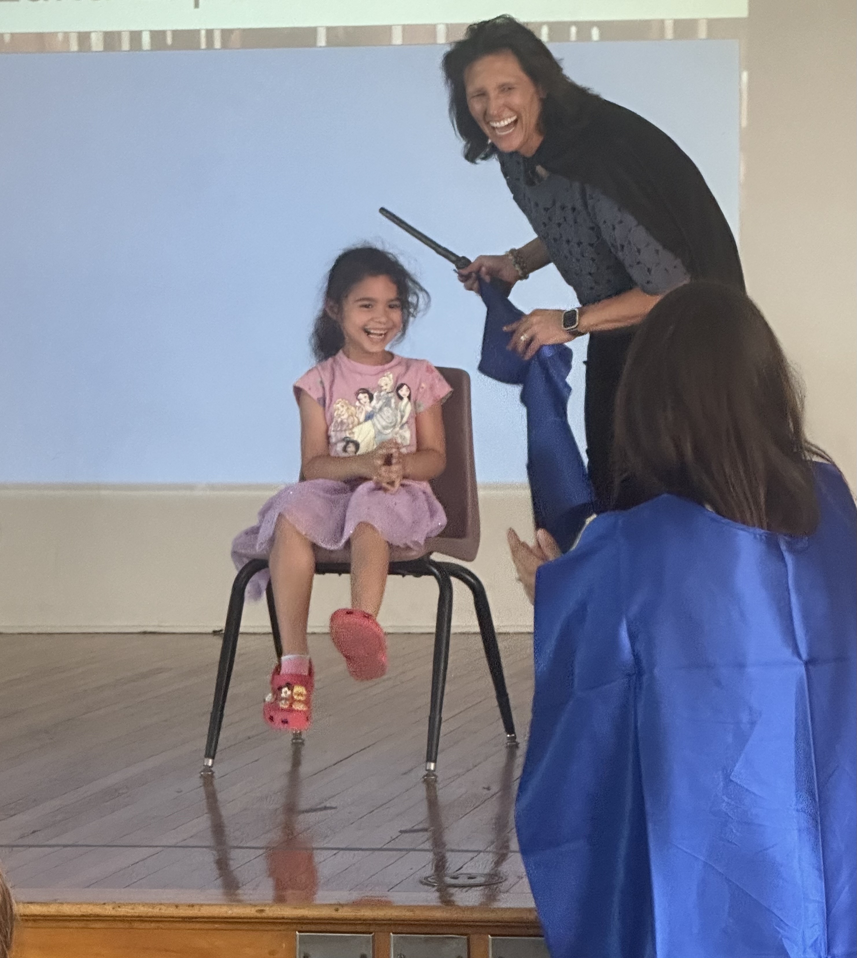 A little girl smiles and laughs with Kellond's principal